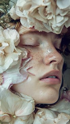 a woman with freckles on her face is surrounded by white flowers and petals