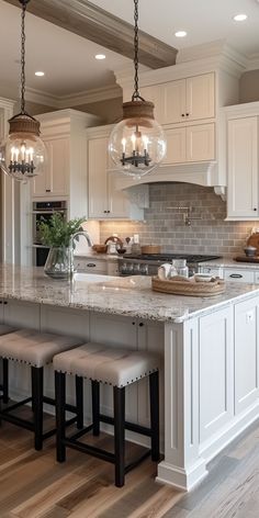 a large kitchen with white cabinets and marble counter tops, two stools at the island