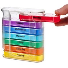 a hand holding a plastic container filled with different colored liquids and writing on the side