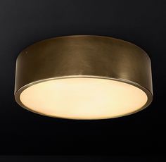 a round light fixture hanging from the ceiling in a dark room with black walls and flooring