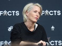 a woman sitting at a table in front of a black sign with the words fact's on it