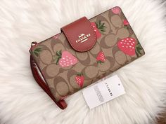 Coach Phone Wallet In Signature Canvas With Wild Strawberry Print Brand New With Tags 100% Authentic Color: Gold/Khaki Multi Signature coated canvas and smooth leather Six credit card slots ID window Snap phone compartment Snap closure Outside zip pocket Attached wrist strap 7 1/4" (L) x 4 1/2" (H) Fits all iPhone and Samsung Galaxy phones Style No. CH165 Coach Strawberry Collection, Coach Strawberry Wallet, Coach Strawberry, Window Snap, Cute Mini Backpacks, Pretty Purses, Birkenstock Boston Shearling, Boston Shearling, Wild Strawberry