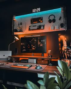 a desk with a computer monitor, keyboard and mouse on it in front of a plant