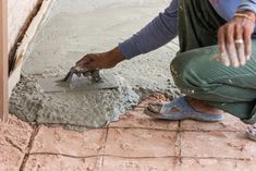 a man is pouring cement onto the floor with his hands and feet on the ground