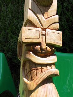 a wooden carving of a totem sitting on top of a green chair