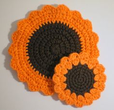 two crocheted flower coasters sitting on top of a table