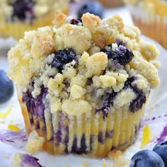 a muffin with blueberries and crumbs sitting on top of a plate