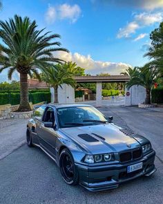 a silver car parked in front of a palm tree