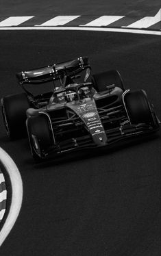 a black and white photo of a race car driving down the track with its front wheels out