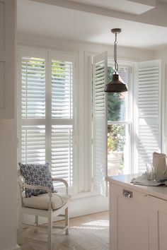 a kitchen with white shuttered windows and an island