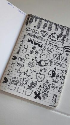 an open notebook with doodles and stickers all over it, on top of a white surface