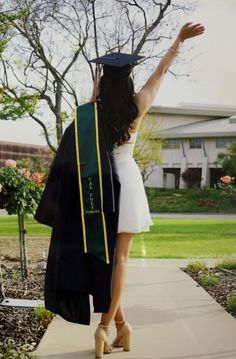 a woman is walking down the sidewalk with her graduation cap and gown over her shoulder