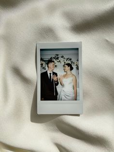 an old photo of a man and woman on a white sheet with flowers in the background