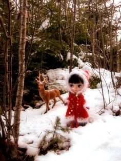 a small stuffed animal in the snow next to some trees and other animals near by