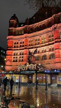 the hog potter's building is lit up at night with people walking around it