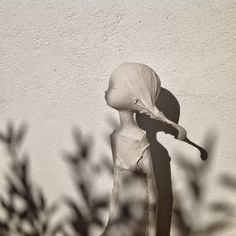 a white statue holding a baseball bat next to a wall