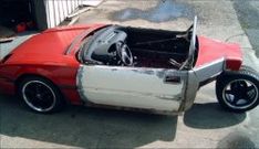 a red and white car parked on the side of a road next to a building