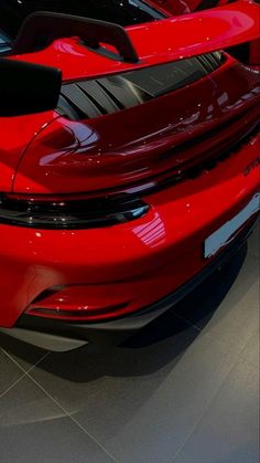 two red sports cars parked next to each other in a showroom with no one around them