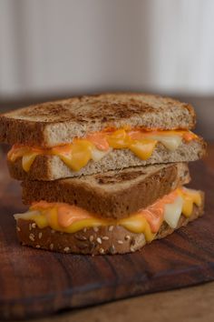 a grilled cheese sandwich sitting on top of a wooden cutting board