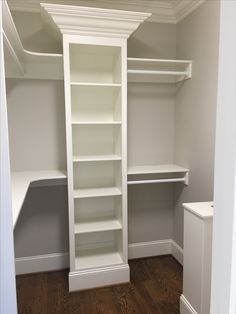 an empty walk in closet with white shelving and wood flooring on the walls