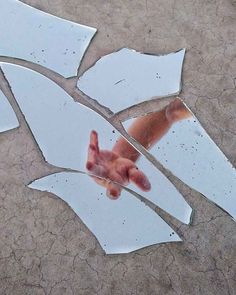 a broken piece of glass with the reflection of someone's hand on it,