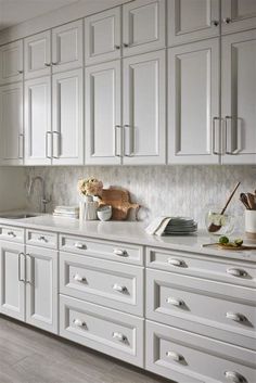 a kitchen with white cabinetry and marble counter tops is pictured in this image from the front view