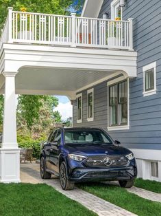 a blue mercedes benz parked in front of a house with white railings and balconies