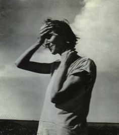 black and white photograph of a man with his hand on his head looking at the sky