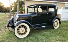 an old black car parked in front of a house