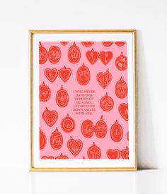 a pink and red print with hearts on it in a gold frame against a white wall