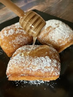 honey being poured onto pastries with powdered sugar on the top and in between