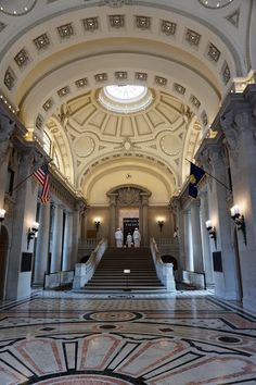 the inside of an old building with marble flooring and arches, along with two flags hanging from the ceiling