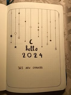 an open notebook with writing on it that says hello 2012 and has stars hanging from the strings