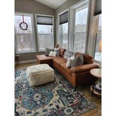 a living room filled with furniture and windows covered in shades of blue, brown and white