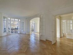 an empty room with wooden floors and large windows