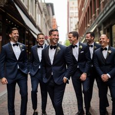 a group of men in tuxedos are walking down the street smiling at each other