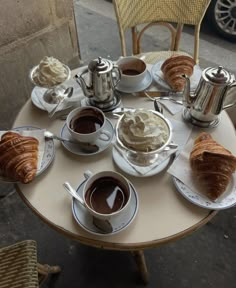 a table topped with cups of coffee and croissants