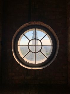 a round window in a brick wall with a view of the city from inside it