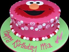 a pink birthday cake decorated with an elmo face