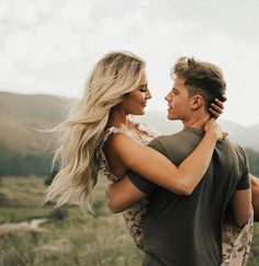 a man and woman embracing each other in an open field