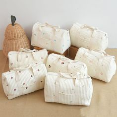 six pieces of white luggage sitting on top of a floor next to a wicker basket