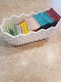 a white bowl filled with lots of different types of papers on top of a counter