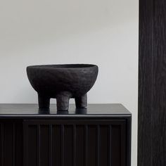 a black bowl sitting on top of a wooden cabinet