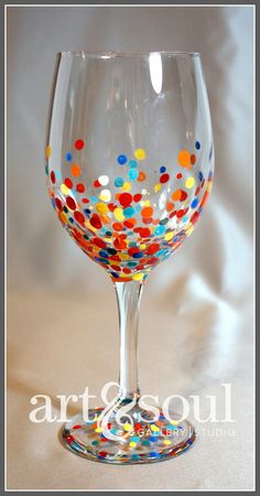 a wine glass filled with colorful confetti on top of a white tablecloth