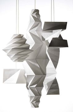 an abstract sculpture hanging from strings in front of a white background with black and white geometric shapes