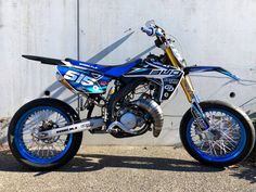 a blue and white dirt bike parked in front of a building