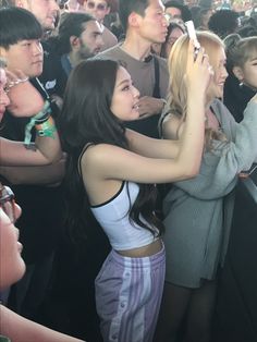 two girls are hugging each other in front of an audience at a concert, one girl is holding her phone up to her ear