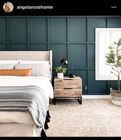 a bedroom with dark green walls and white carpeted flooring, a bed in the center