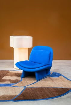 a blue chair sitting on top of a rug next to a lamp