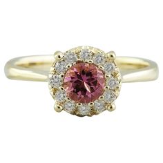 a yellow gold ring with an oval cut pink diamond surrounded by small white and yellow diamonds